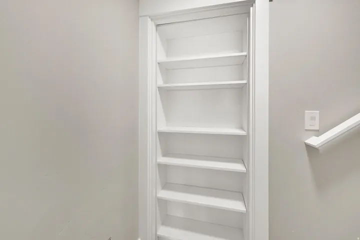 Built-in shelving unit that doubles as a door into utility room with multiple shelves and white trim