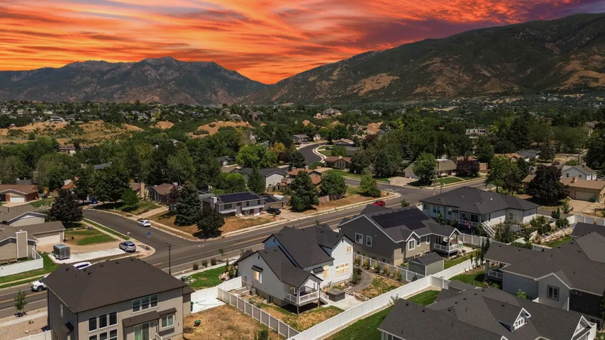 Residential community featuring a variety of single-family homes with dark shingle roofs, surrounded by mature trees