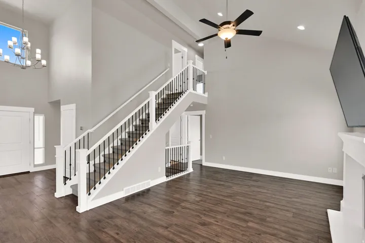 Spacious living area featuring high vaulted ceilings, wood-finish flooring, and a contemporary chandelier