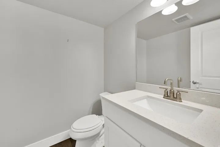 Half bathroom vanity featuring a light-colored countertop with an integrated sink, brushed nickel faucet, and a large wall-mounted mirror