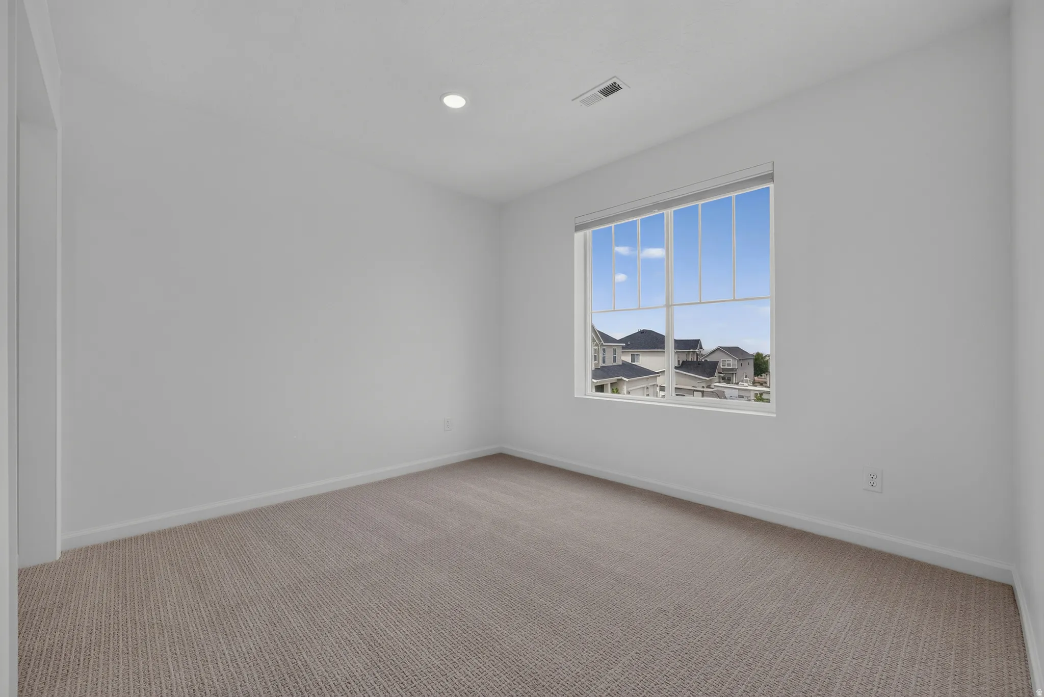 Neutral tone wall finishes, recessed ceiling lighting, and a large window with white framing