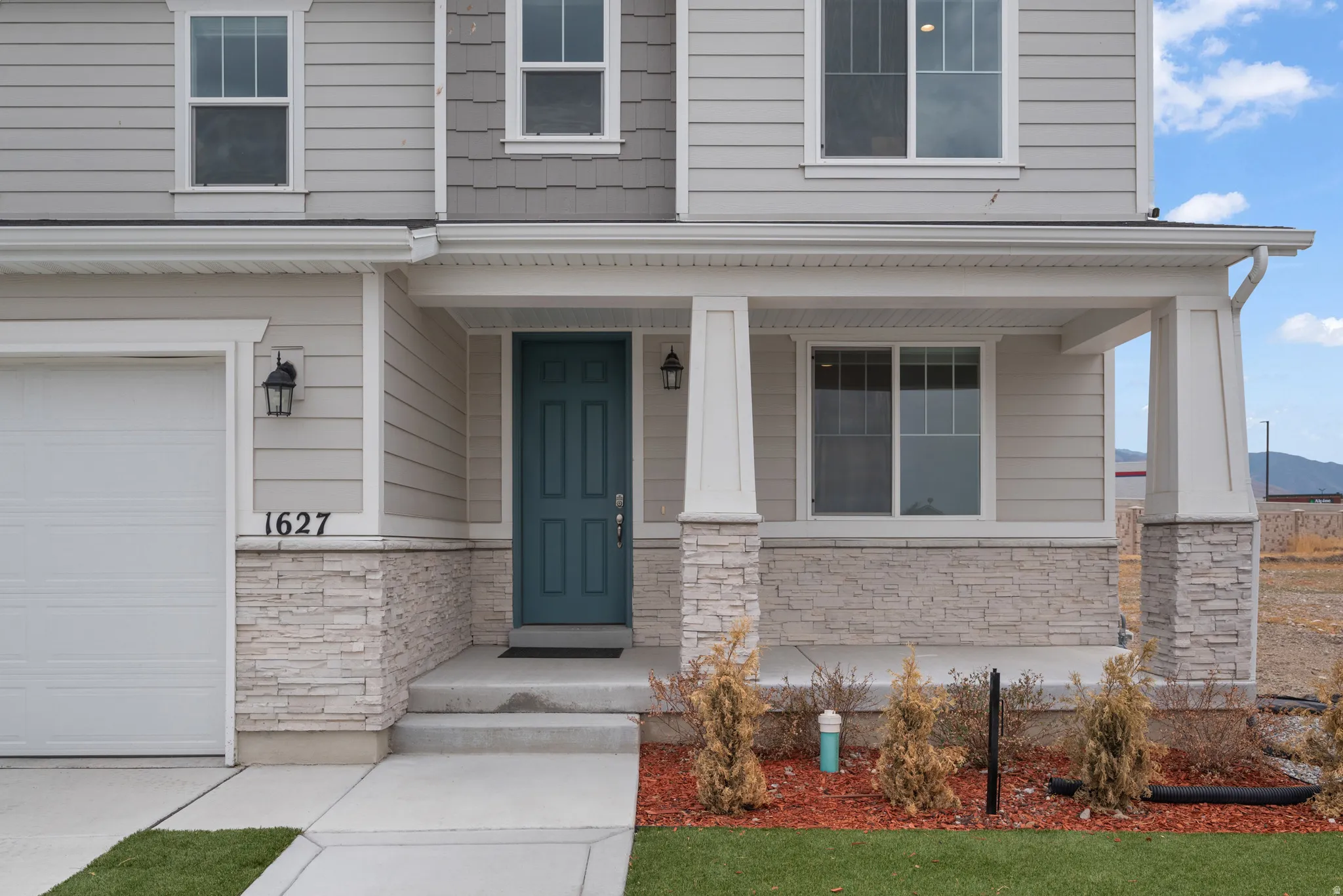 Property exterior showcasing a light-colored siding facade with a contrasting teal entry door
