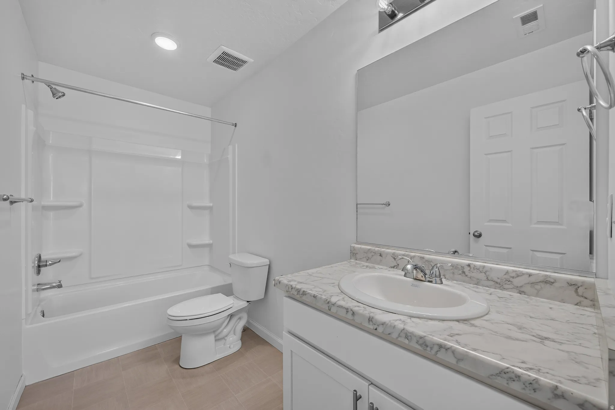 Bathroom featuring a tub/shower combination, white vanity with an integrated sink, and a stone-finish countertop