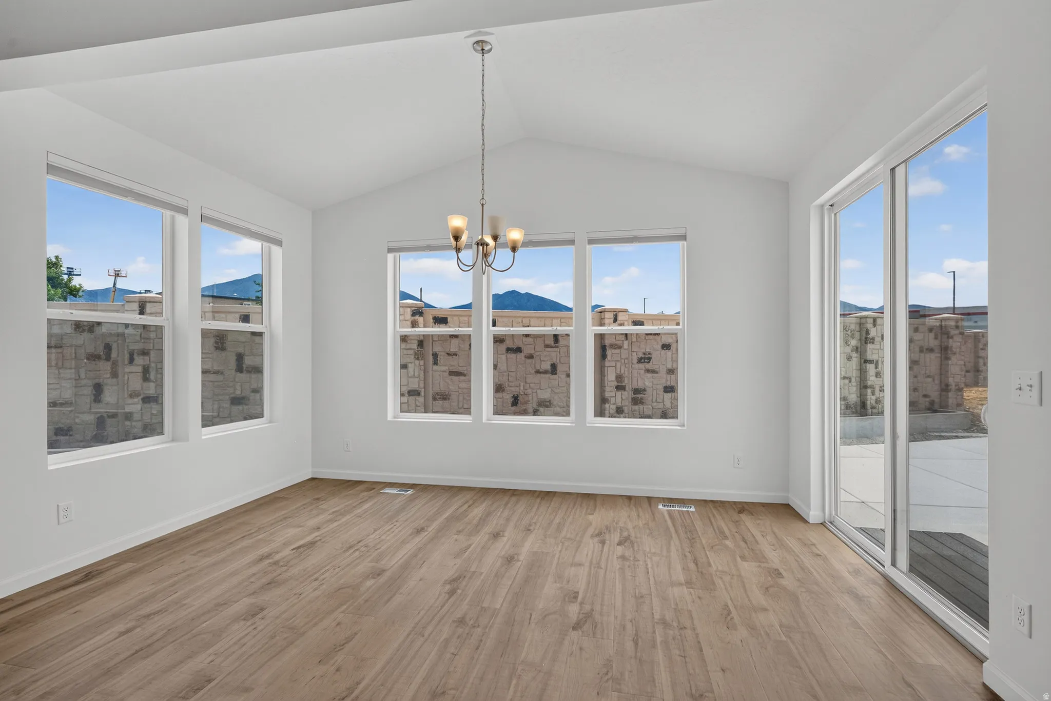 Spacious room featuring vaulted ceilings and wood-finish flooring