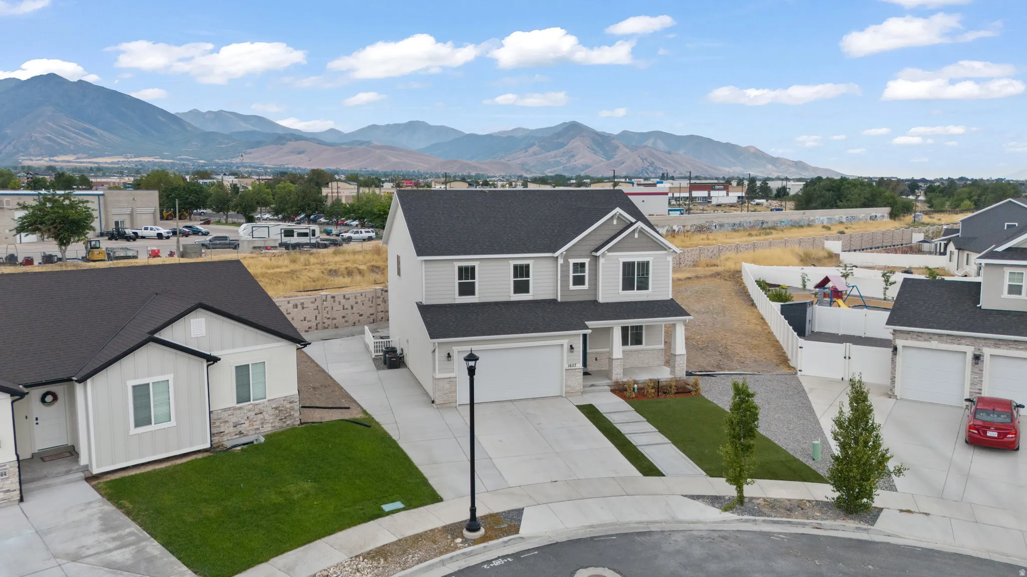 Two-story residence featuring light gray siding with stone veneer accents and a dark shingle roof