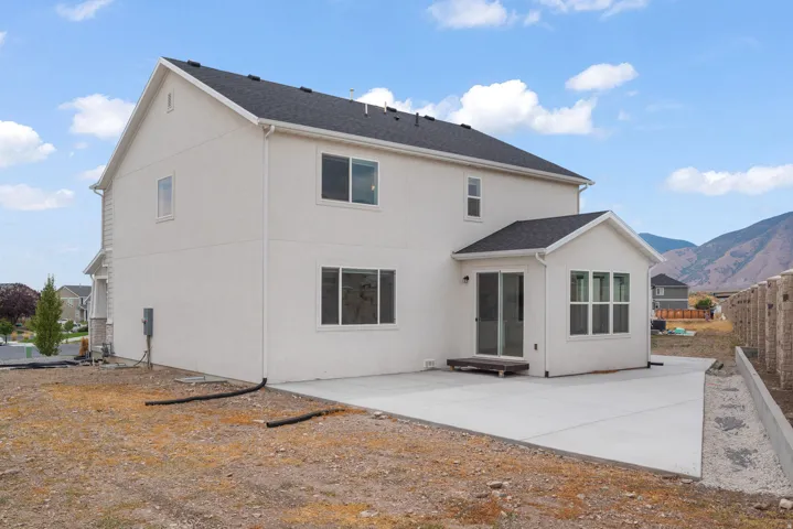 Rear exterior featuring a spacious concrete patio, a sunroom with multiple windows, and sliding glass doors