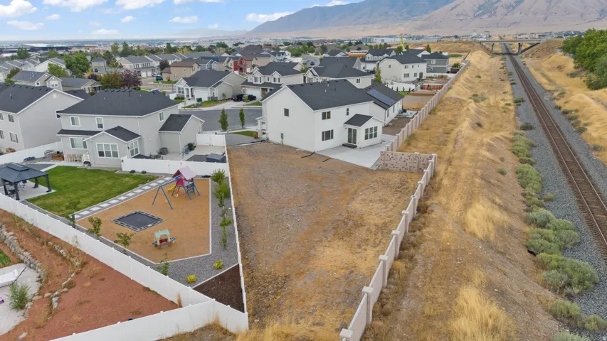 Expansive undeveloped lot presenting a blank canvas for customization, featuring a concrete retaining wall, and a durable fence along the perimeter