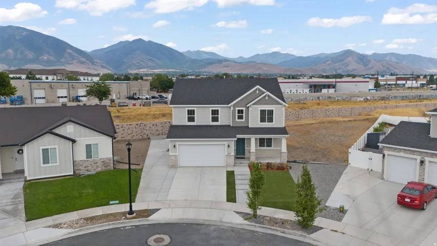 Two-story residence featuring light gray siding with stone-look accents, a dark shingled roof, and a two-car garage