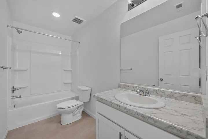 Bathroom featuring a tub/shower combination, white vanity with an integrated sink, and a stone-finish countertop