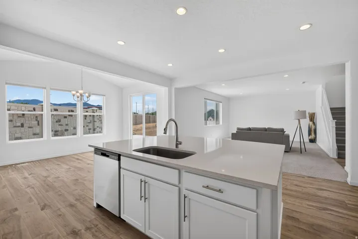 Kitchen island featuring an undermount sink, gooseneck faucet, and white cabinetry with brushed nickel hardware