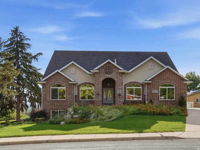 Brick exterior with arched window details, gabled roofline, and established landscaping