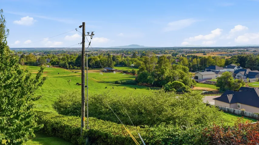 Expansive landscape with a clear sky, distant mountain ranges, and scattered residential properties