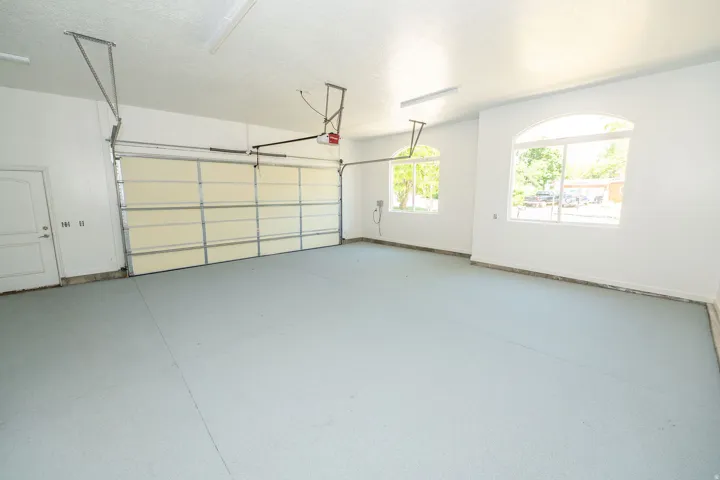 Spacious garage featuring a light gray epoxy floor coating, two arched windows, and a segmented garage door with an automatic opener