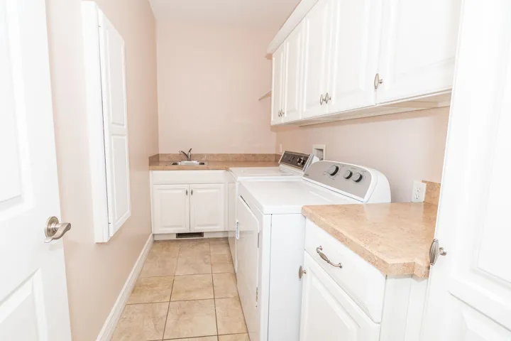 Laundry room featuring white cabinetry, a utility sink, and stone-finish countertops