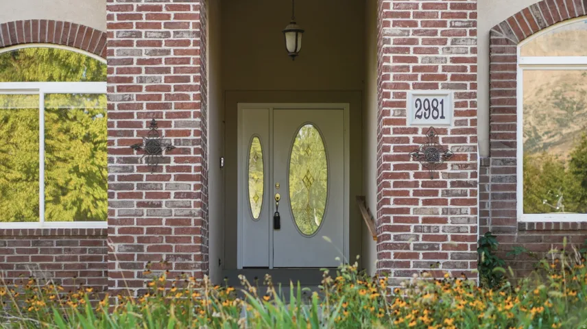 Brick facade with arched windows, double entry doors with oval glass inserts, and a covered porch