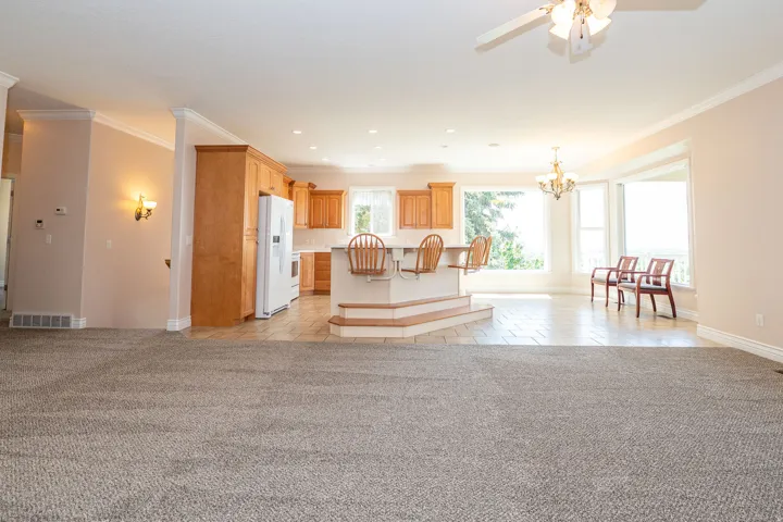 Expansive open-concept living area featuring a kitchen with light wood cabinetry, a tiered island with seating, and tile flooring