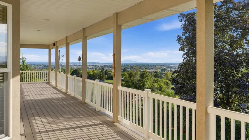 Expansive covered porch featuring wood-finish decking and white railings