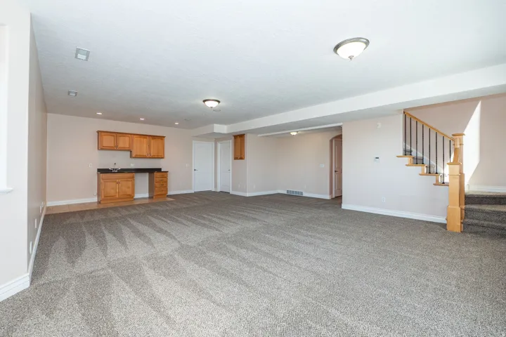 Spacious recreation area featuring a built-in wet bar with wood cabinetry and a dark countertop