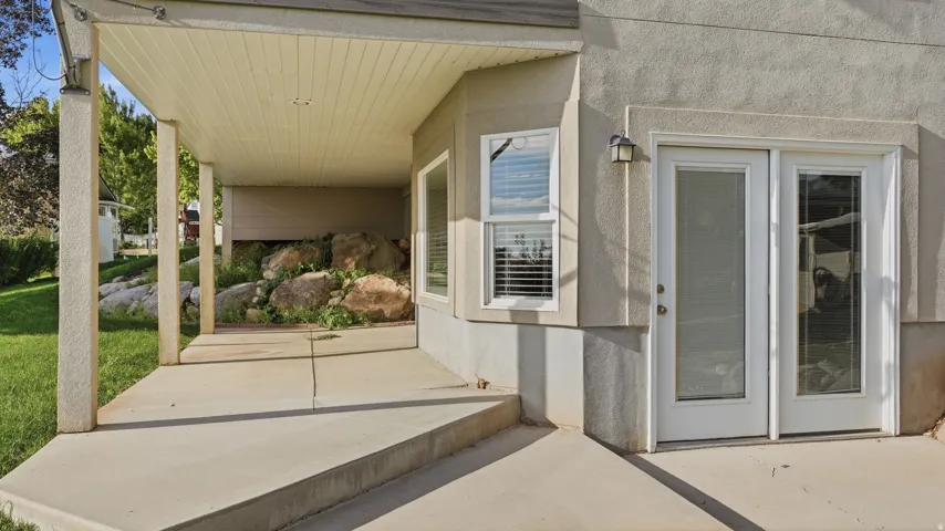 Covered concrete patio with overhead lighting, featuring a stucco exterior and sliding glass doors