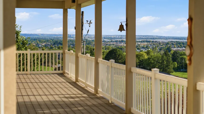 Expansive covered porch with a composite deck, classic white railings, and a wide-ranging distant landscape