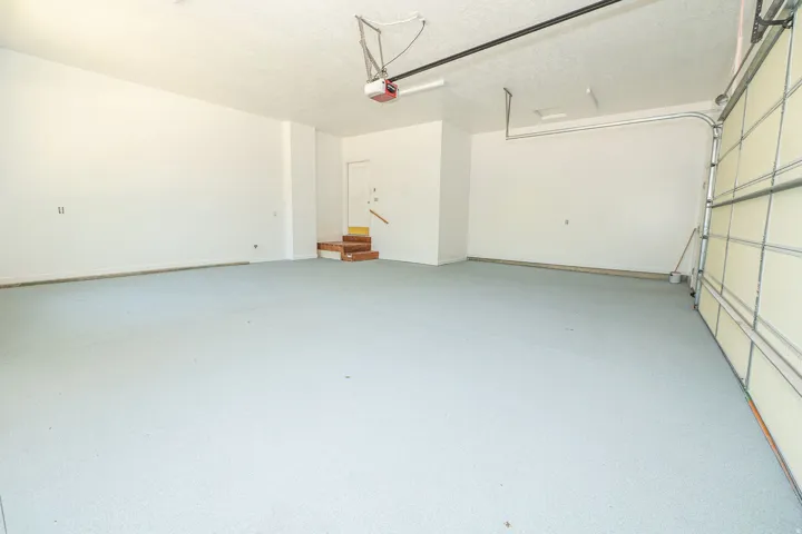 Spacious garage featuring a light gray speckled floor finish, white walls, and an automatic garage door opener