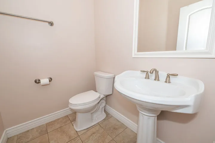 Pedestal sink with brushed nickel faucet, framed mirror, and tile flooring