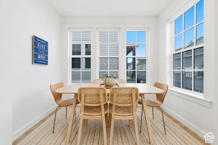 Bright dining area featuring white walls, large multi-pane windows, and light wood-finish flooring