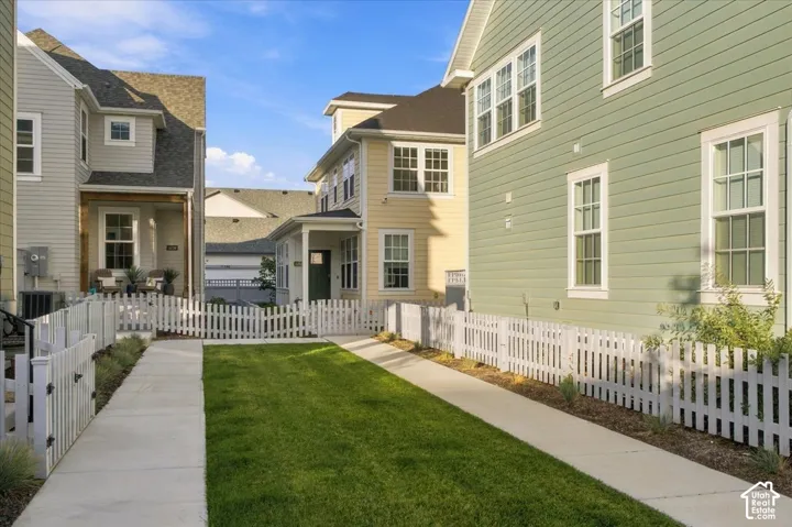 Manicured lawn area enclosed by white picket fencing with concrete pathways
