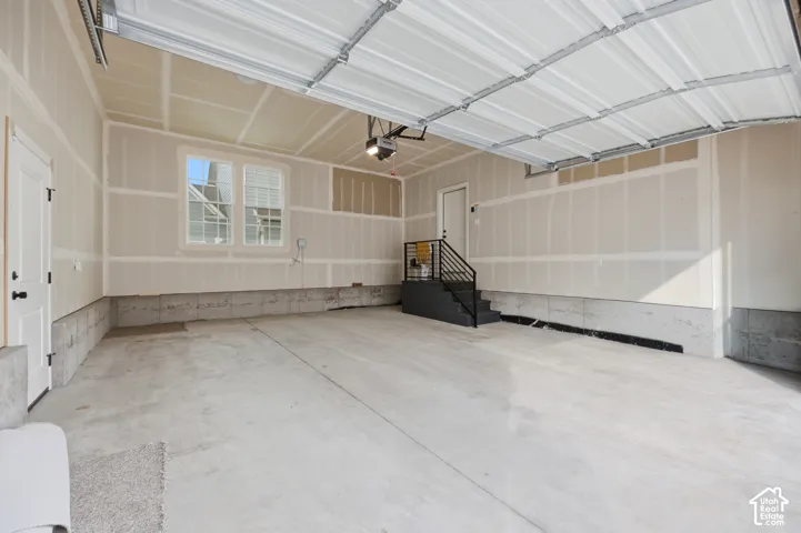 Spacious garage featuring a concrete floor, a window with exterior views, and a metal staircase with a black handrail