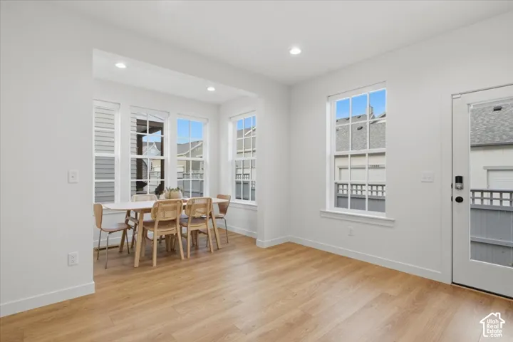 Neutral-toned interior featuring wood-finish flooring, recessed lighting, expansive multi-pane windows, and a glass-paneled exterior door