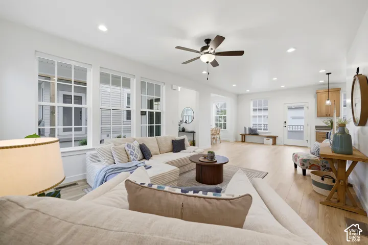 Spacious living area featuring light wood-finish flooring and abundant natural light from multiple large windows