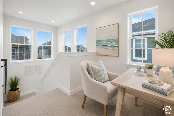 Versatile loft space featuring multiple large windows, recessed lighting, neutral carpeting, and a white painted banister