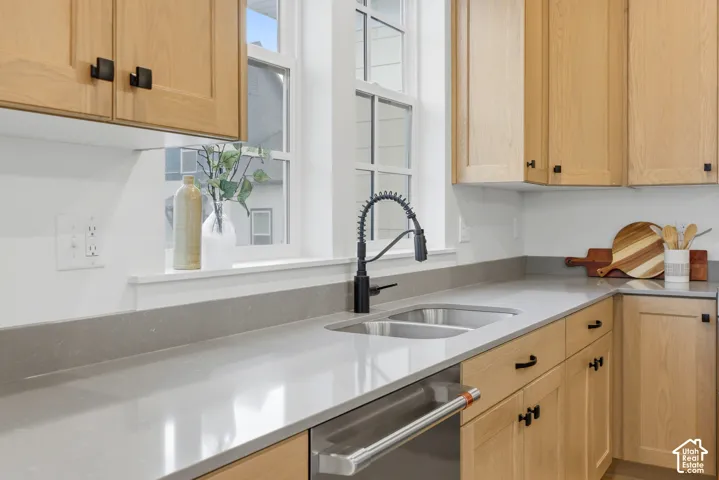 Kitchen featuring light wood cabinetry, matte black hardware, gray countertops, a double basin stainless steel sink, and a black gooseneck faucet