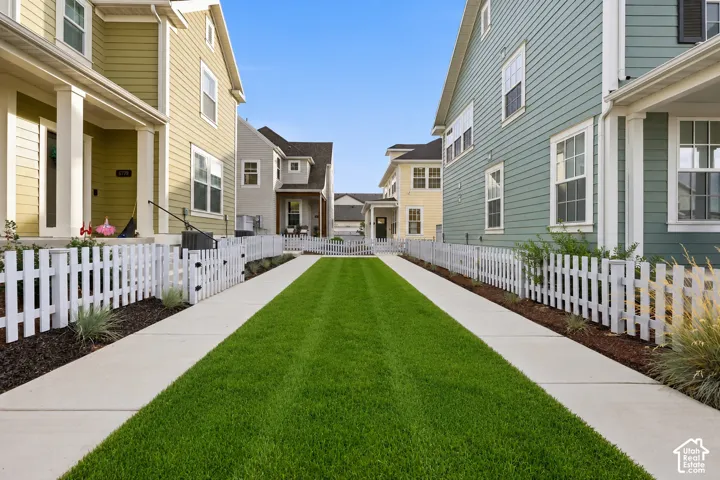 Central green space with a manicured lawn framed by concrete pathways and white picket fences