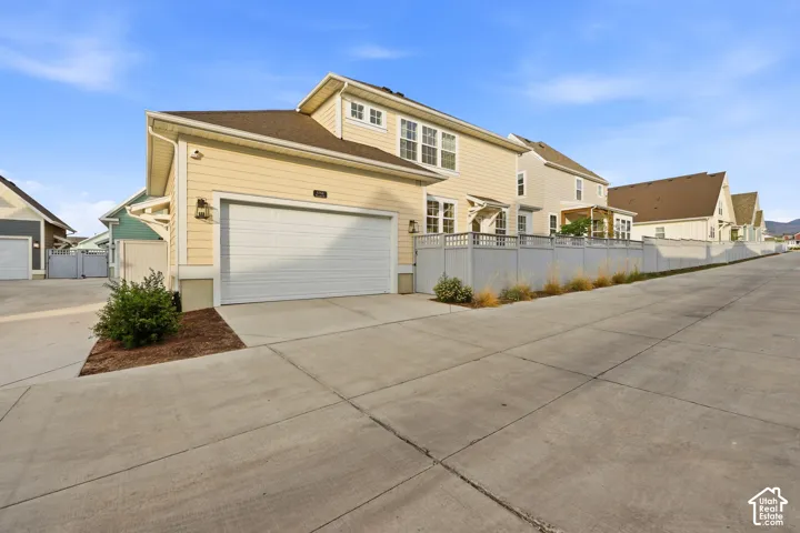Rear exterior featuring horizontal siding, a two-car garage with a white roll-up door, and a second-story dormer