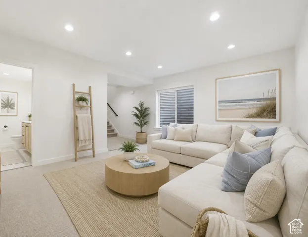 Recessed lighting illuminates the carpeted living area, featuring a built-in window and an open doorway revealing a bathroom with a wood-finish vanity
