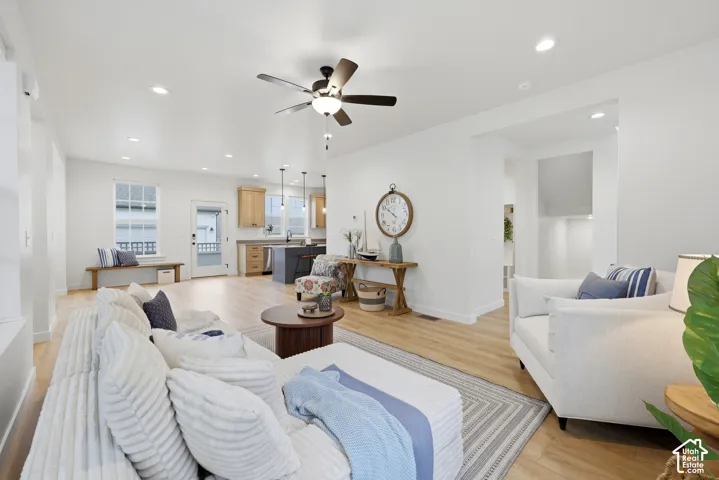 Open-concept living area with light wood-finish flooring and recessed lighting