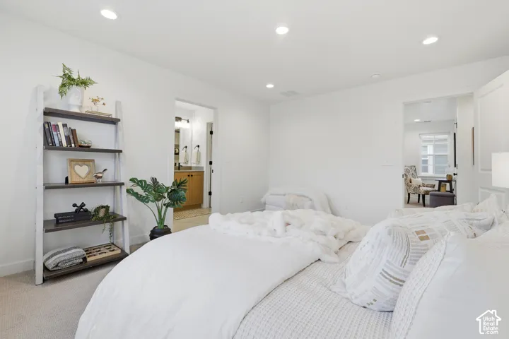 Bedroom featuring recessed lighting, carpet flooring, and a doorway leading to a bathroom with a wood-finish vanity and mirror