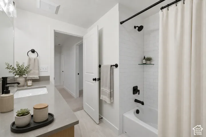 Bathroom featuring a single vanity with a solid surface countertop, an undermount sink, and a matte black faucet