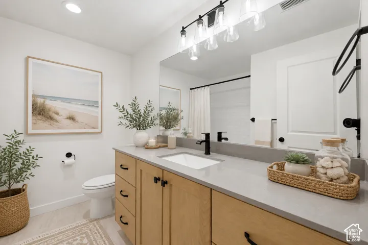 Modern bathroom featuring a single vanity with light wood cabinetry, a light gray countertop, and an undermount sink
