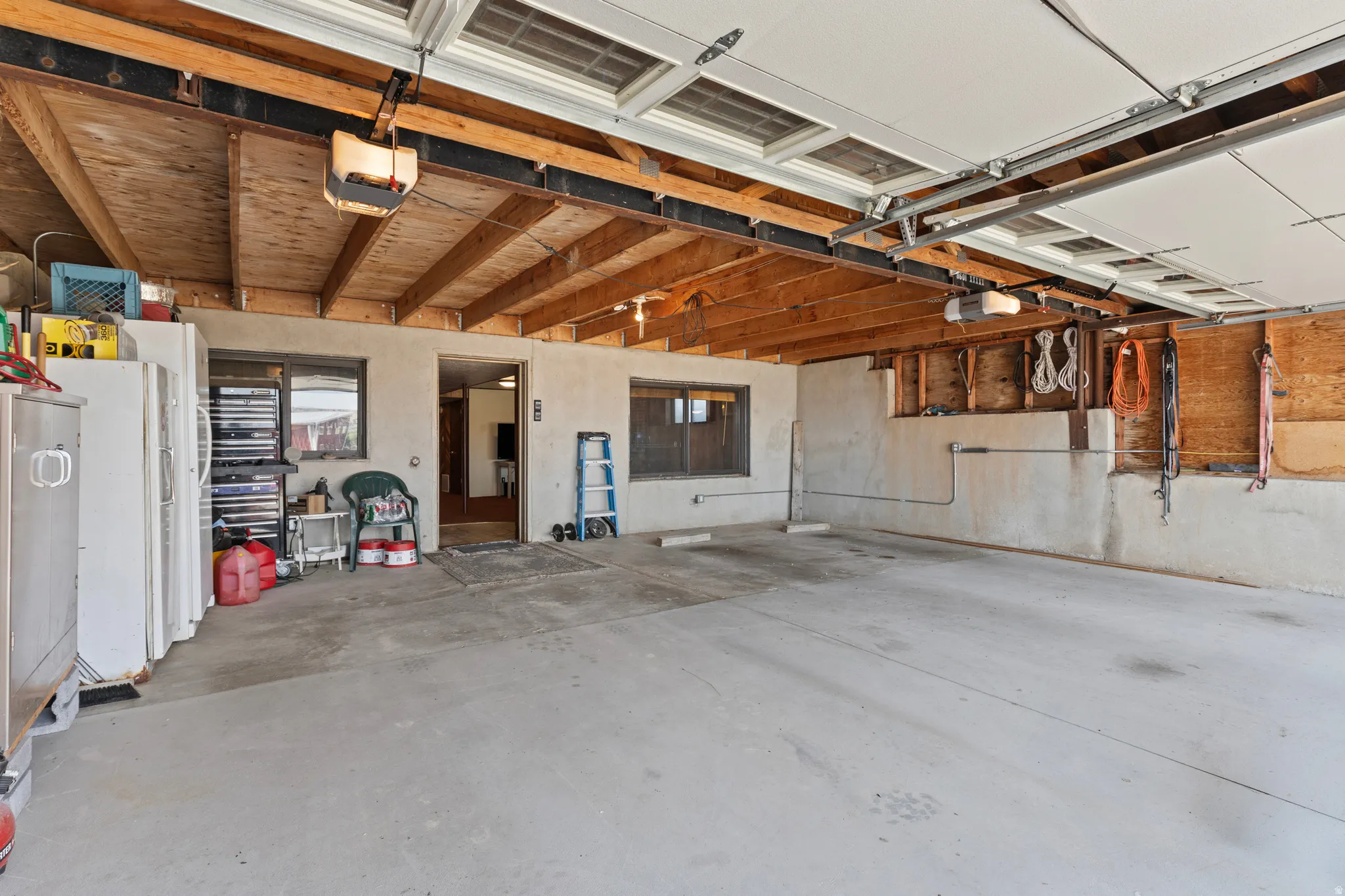 Spacious 2 car garage with exposed wood beam ceiling, concrete flooring, and an automatic garage door opener