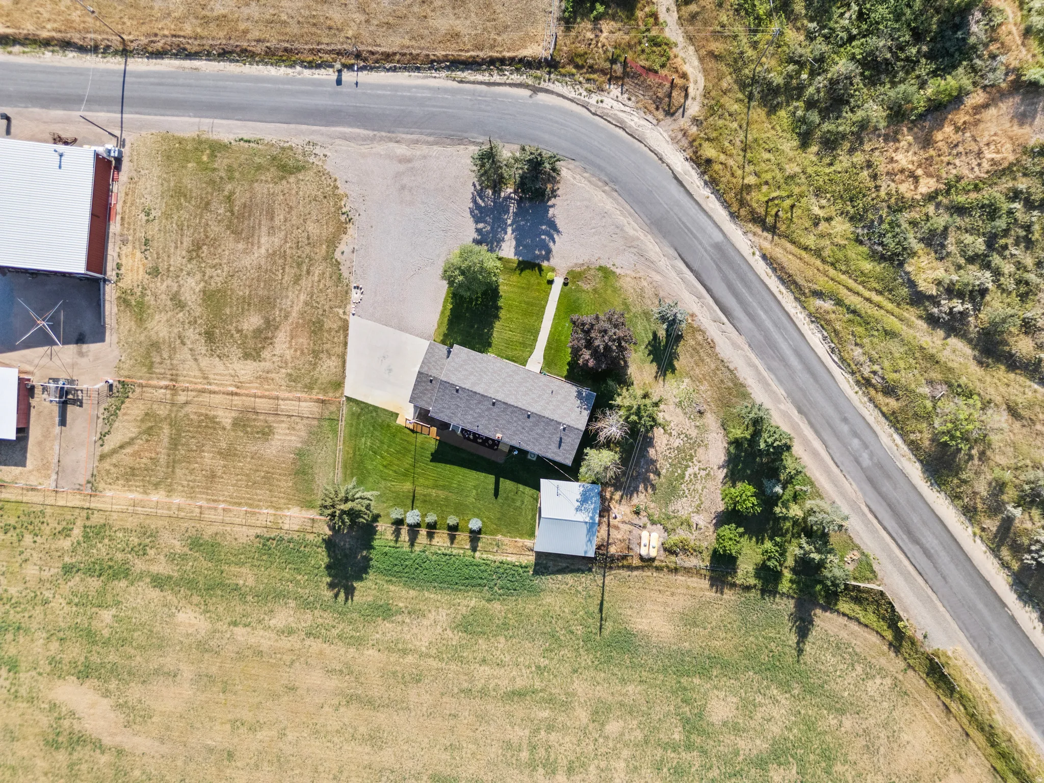 Single-story residence featuring a shingle roof, a concrete driveway, and surrounding green lawn areas
