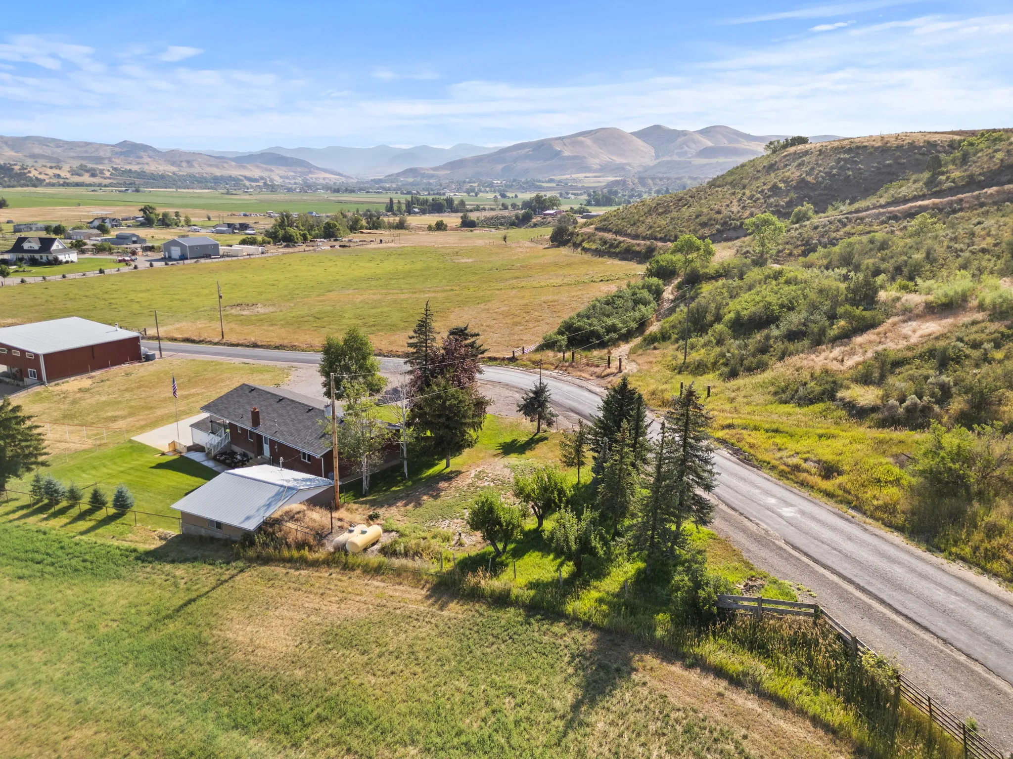 Expansive property featuring a residence with a covered deck, and a smaller outbuilding with a metal roof