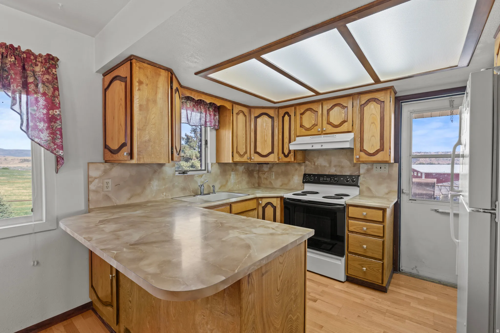 Kitchen featuring natural wood cabinetry, a range, and a breakfast bar