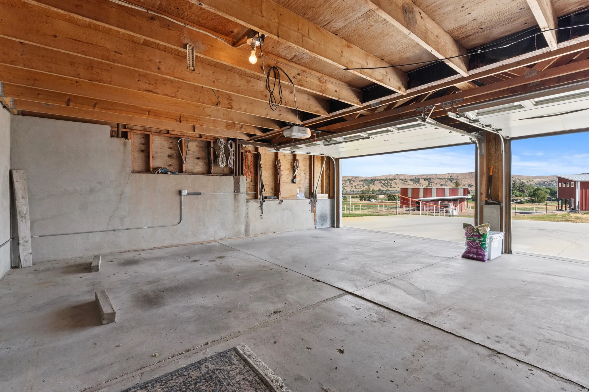Spacious 2 car garage interior with concrete flooring and exposed wood ceiling beams