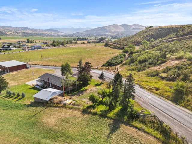 Expansive property featuring a residence with a covered deck, and a smaller outbuilding with a metal roof