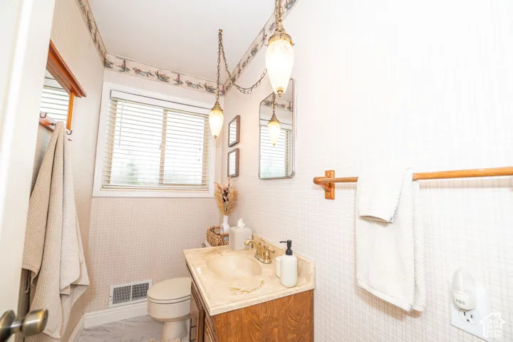 Bathroom featuring a vanity with an integrated sink and base cabinet, a window with horizontal blinds, and two pendant light fixtures