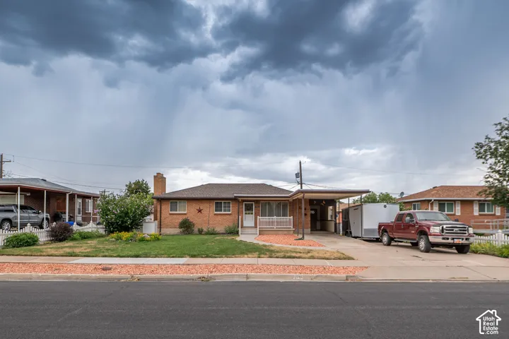 Brick exterior home featuring a covered front porch, carport, and a gravel accent strip
