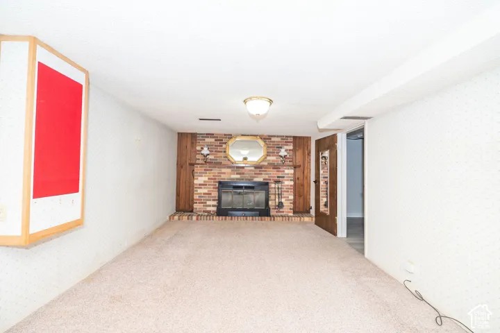 Spacious room featuring a brick fireplace with a black insert, flanked by wood paneling