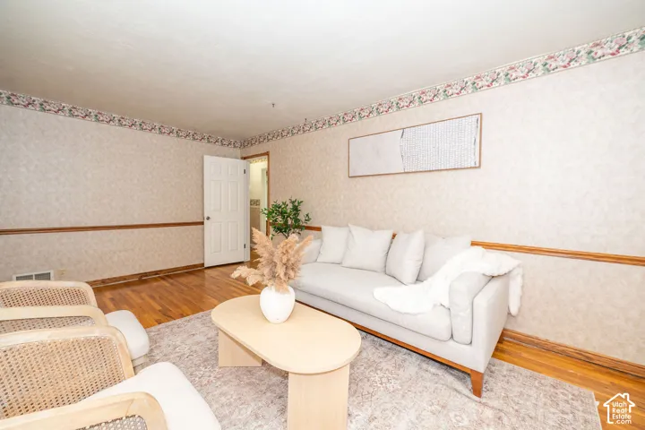 Interior room with hardwood flooring, wallpapered walls, and decorative chair rail molding